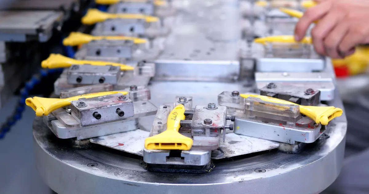 Several metal parts clamped in one multi-part fixture on a machine table, as used when a CNC prototype goes to production
