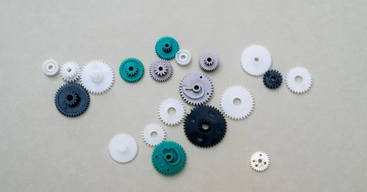 Small plastic gears in white and green on a flat surface, an example of parts used in plastic CNC machining